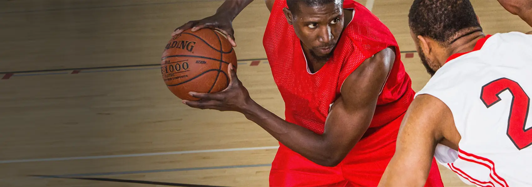 Two basketball players. One with ball, the other guarding.